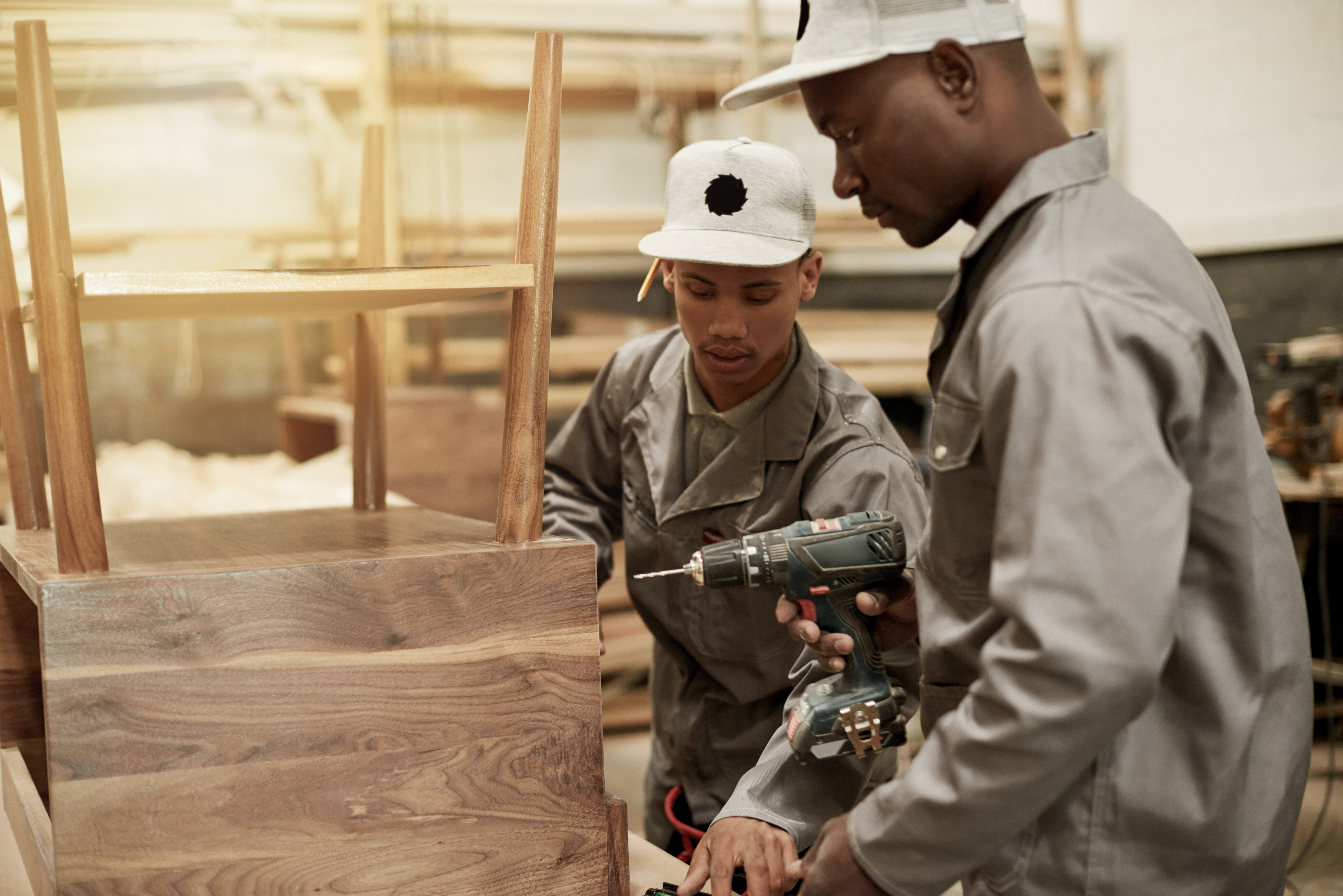 Cropped shot of two young male carpenters putting together a wood piece in their workshop